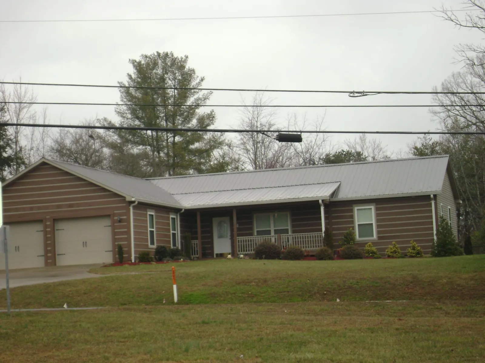 Gray metal roof on a log sided ranch home with a front porch in Merrill